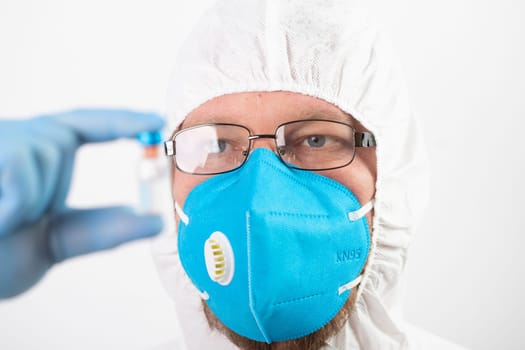 COVID-19 coronavirus vaccine. Vaccination concept. Doctor's hand in blue gloves hold medicine vaccine vial bottle and syringe.