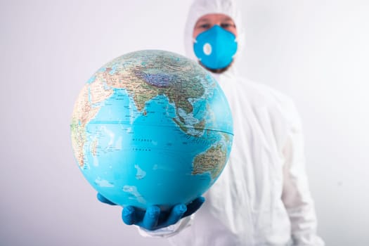 World epidemic danger concept. Male doctor man in medical face mask and gloves protecting planet Earth.