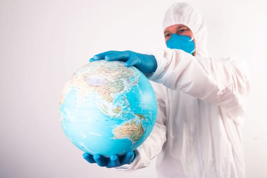 World epidemic danger concept. Male doctor man in medical face mask and gloves protecting planet Earth.