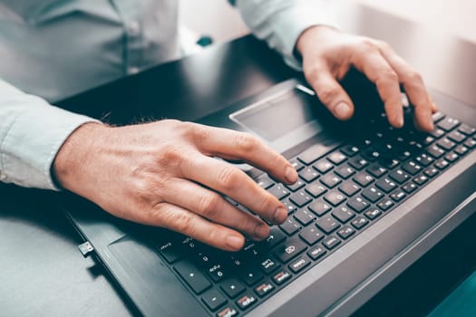 Close up of business man hand working on laptop computer on wooden desk as concept