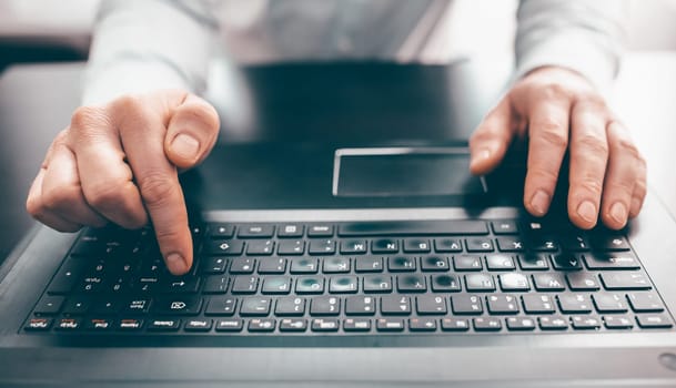 Close up of business man hand working on laptop computer on wooden desk as concept