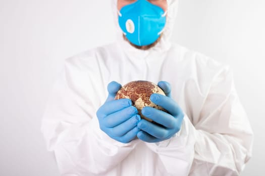 World epidemic danger concept. Male doctor man in medical face mask and gloves protecting planet Earth.