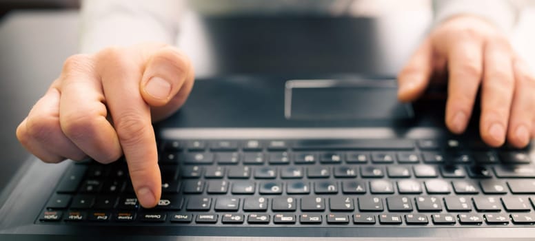 Close up of business man hand working on laptop computer on wooden desk as concept