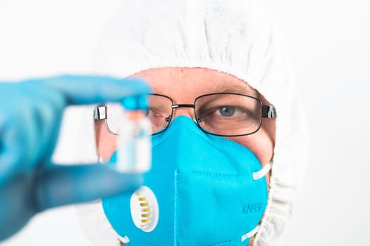 COVID-19 coronavirus vaccine. Vaccination concept. Doctor's hand in blue gloves hold medicine vaccine vial bottle and syringe.