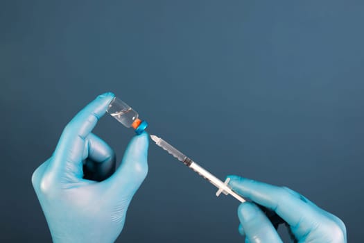 COVID-19 coronavirus vaccine. Vaccination concept. Doctor's hand in blue gloves hold medicine vaccine vial bottle and syringe.