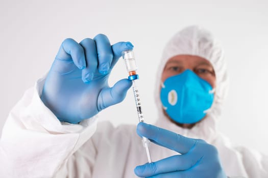 COVID-19 coronavirus vaccine. Vaccination concept. Doctor's hand in blue gloves hold medicine vaccine vial bottle and syringe.