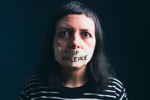 Women violence and abused concept. Stop domestic violence against women and human trafficking.Woman with tape on mouth and stop violence text