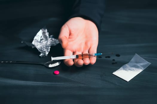 Drug addict reaches for another dose of drug. Concept of addiction, antidrug. International Day against Drug Abuse.