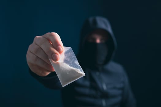 Hand of addict man holding a dose of cocaine or heroine. Concept of drug dealer, drug trafficking, crime, addiction and sale.
