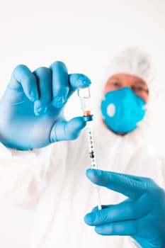 COVID-19 coronavirus vaccine. Vaccination concept. Doctor's hand in blue gloves hold medicine vaccine vial bottle and syringe.