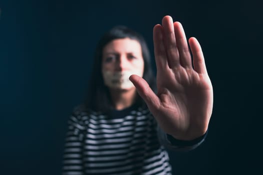 Women violence and abused concept. Stop domestic violence against women and human trafficking.Woman with tape on mouth and stop violence text