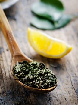 Green tea in wooden spoon and lemon slice