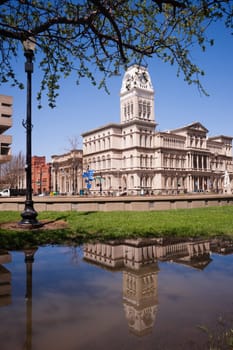 City Hall is reflected in water that has collected in the park across the street during recent flooding