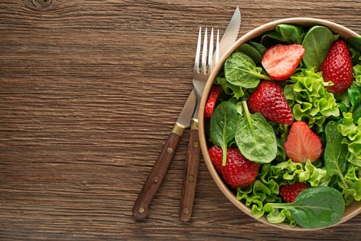 Healthy green salad with strawberry on wooden table background. Healthy salad meal