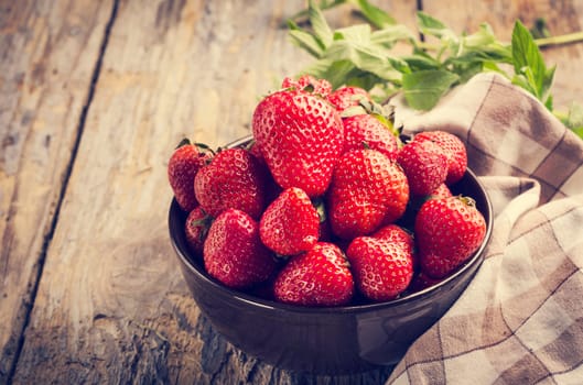 .Strawberries in bowl on rustic table.