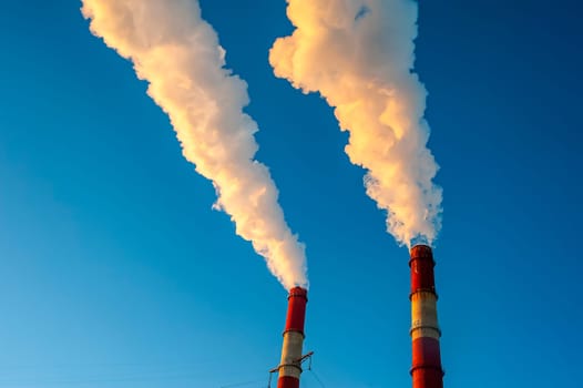 white smoke is coming out of the pipes in the blue sky. High quality photo