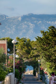 A small alley towards the sea in the apartment complex Lučica on the island of Vir, Croatia. View of the sea and the mountains.