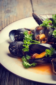 Mussels in tomato sauce on rustic wooden table