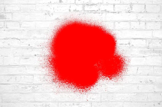 White brick wall with red graffiti spray