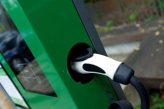 EV Car or Electric car at charging station with the power cable supply plugged .
