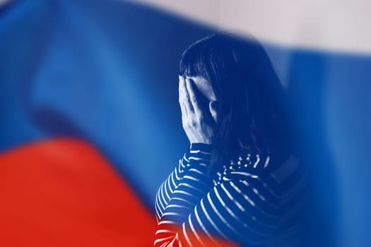 War between Russia and Ukraine. Woman with sad sight, Stop text over Russian flag.