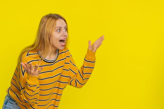 Oh my God wow. Excited amazed winner woman appears from below in surprise looking at camera with big eyes shocked by sudden victory celebrating success achievement good news. Girl on yellow background