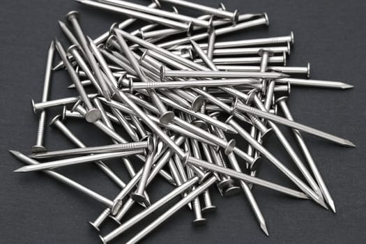 Pile of silver metallic nails on black background