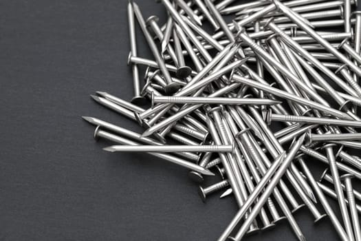 Pile of silver metallic nails on black background
