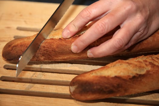 Cutting fresh baked French Baguette
