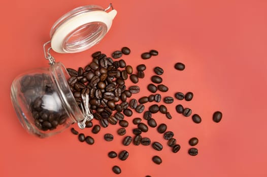 Roasted Coffee beans in a glass jar top view on pink background with copy space. Represent breakfast, energy, freshness or aroma