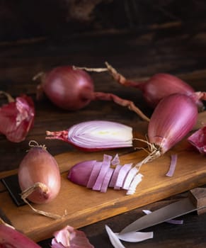 Sliced Red tropea onions with a knife on a wooden board close up. Traditional local south italian vegetable. Cooking process in home kitchen