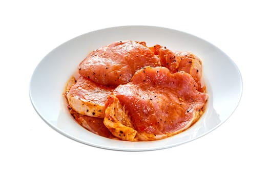 Pork in marinade lies on a white plate on a white isolated background. High quality photo