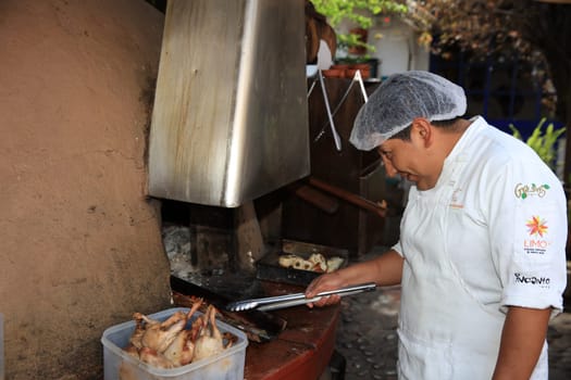 Man at the Restaurant Pachapacha in Cusco grills Guinea Pig – the traditional Meal in Peru