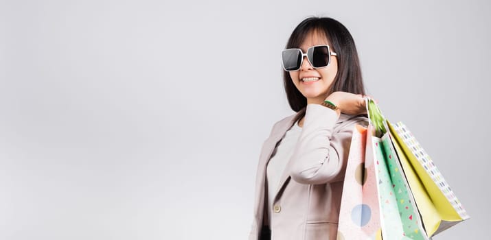 Happy woman with glasses confident shopper smiling holding online shopping bags colorful multicolor, Portrait excited Asian young female purchase studio shot isolated on white background, fashion sale