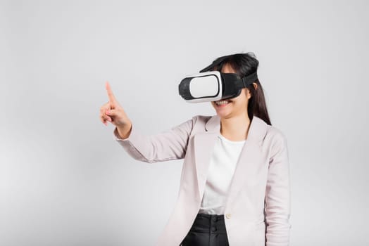 Smiling woman confidence wearing VR headset device touching air during virtual reality experience isolated white background, Asian happy portrait female playing video game studio shot, copy space