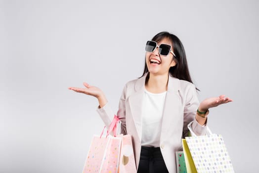 Woman with glasses confident shopper smiling holding online shopping bags colorful multicolor, Portrait excited happy Asian young female person studio shot isolated on white background, fashion sale