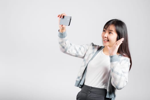 Woman excited holding smartphone to shooting selfie photo front camera studio shot isolated white background, happy young female smiling taking photography by mobile phone on mobile phone