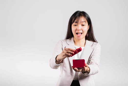 Smiling woman confidence opening a red gift box on palm isolated white background, surprise birthday or Christmas day and valentine, Asian happy portrait beautiful young female studio shot, copy space