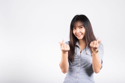 Woman standing her smile confidence showing mini heart sign with her finger isolated white background, Asian happy portrait beautiful young female send love and happy valentine in studio shot
