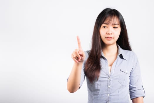 Woman standing her smile confidence with touching an imaginary screen with her finger isolated white background, Asian happy portrait beautiful young female pushing on button in studio shot