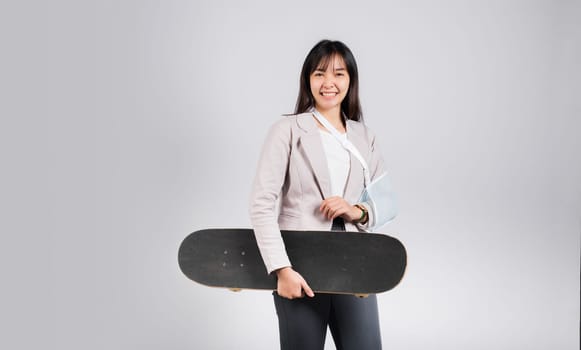 Woman smile broken arm after accident wear arm splint for treatment she play skateboard skating accident sport extreme, happy Asian female sling support hand isolated on white background, copy space