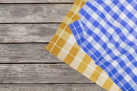 Empty table product. Top view of a rustic wooden table with a blue and a yellow checked tablecloth or napkin. Template for your food and product presentation montage. Space for food recipes.