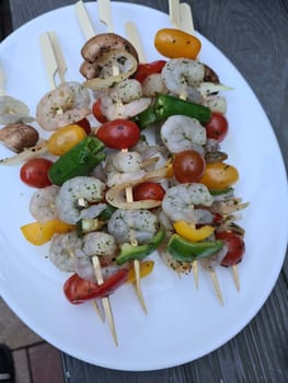 Grilled shrimp skewers. Seafood, shelfish. Shrimps Prawns skewers with herbs, garlic and lemon on black stone background, copy space. Shrimps prawns brochette kebab. Barbecue srimps prawns.