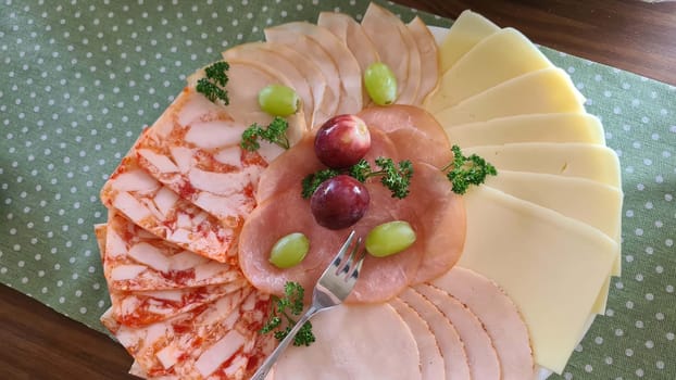 Food tray with delicious salami, pieces of ham, sausage, tomatoes, lettuce and vegetables - meat platter with selection - cut sausage and sausage on a celebratory table.