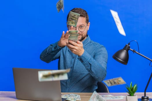 Caucasian rich man wasting throwing sharing money dollar cash around more tips big profit winning lottery casino jackpot, successful shopping payment purchase cashback. Guy isolated on blue background