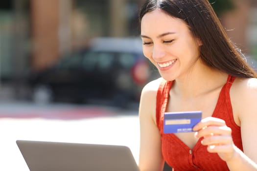 Happy asian woman paying online with credit card
