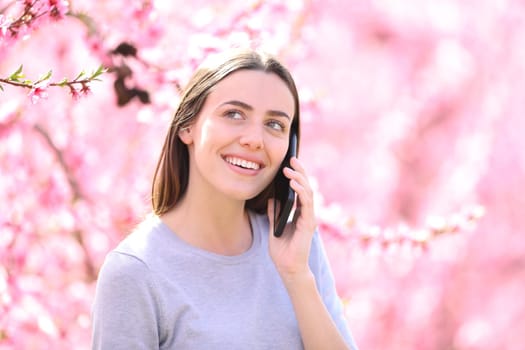 Happy woman talking on phone in a pink flowered field
