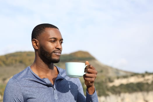 Man with black skin drinking and contemplating outdoors