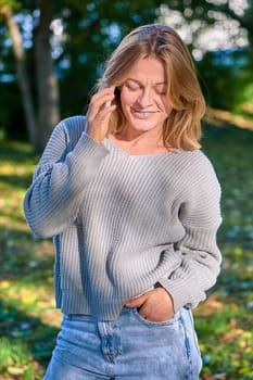 Beautiful woman talking on the phone in the park in summer. High quality photo