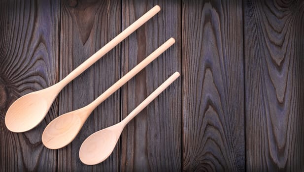 The three wooden spoons on a dark wood table with copy space